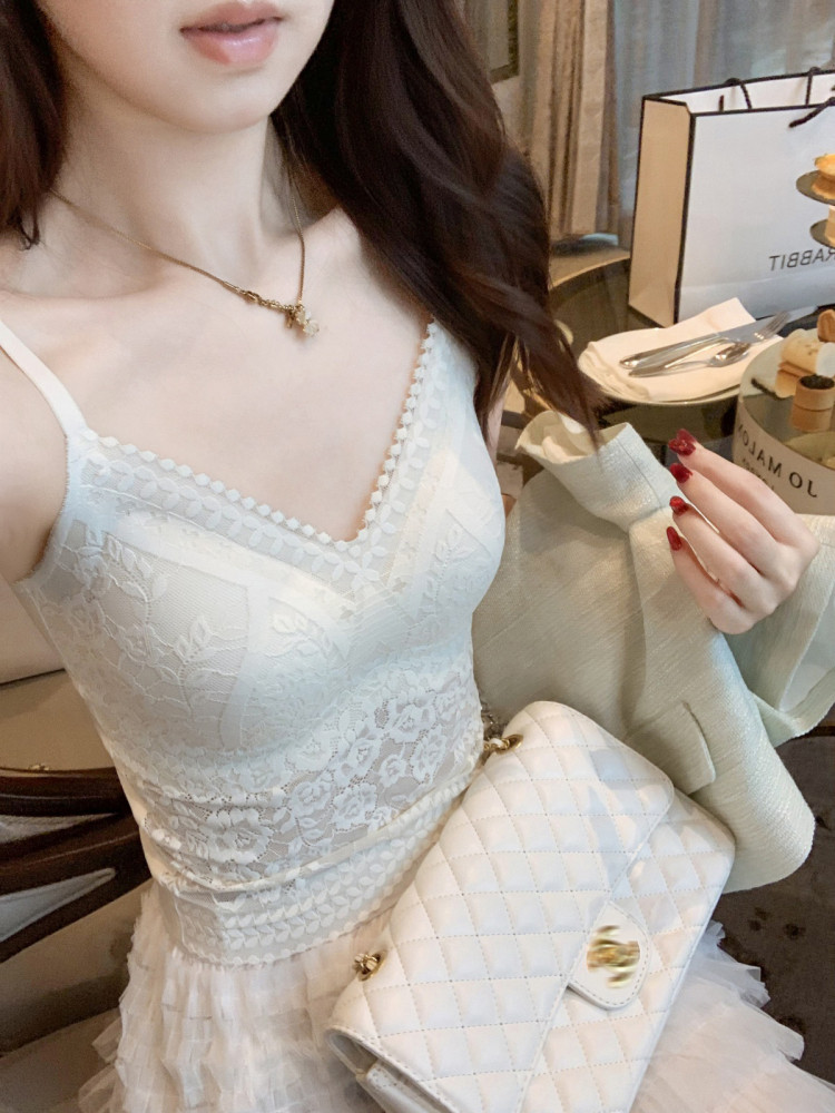 Woman wearing a white lace spaghetti-strap dress and holding a quilted white handbag