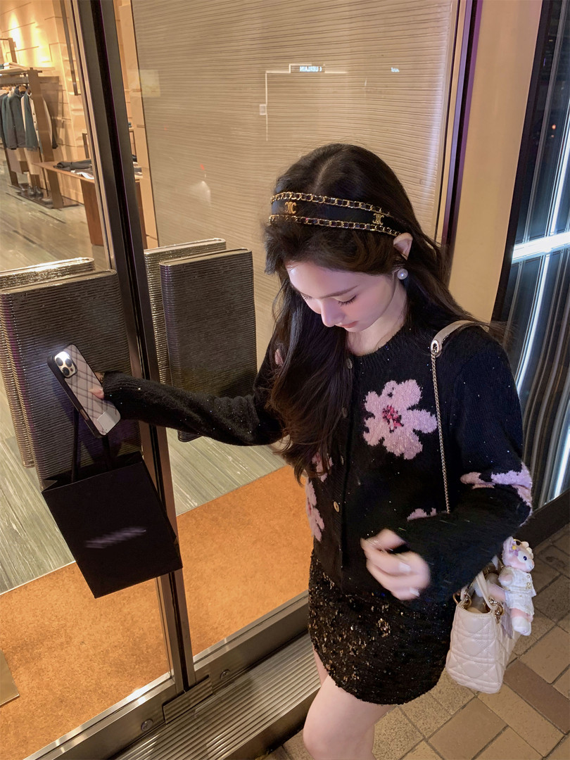 Woman wearing a black floral cardigan and sparkly skirt with a headband and handbag