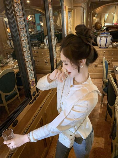 Woman wearing a white long-sleeve top with jeans and a quilted crossbody bag