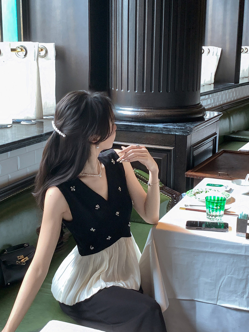 Woman wearing a black sleeveless top with a white skirt in a restaurant setting