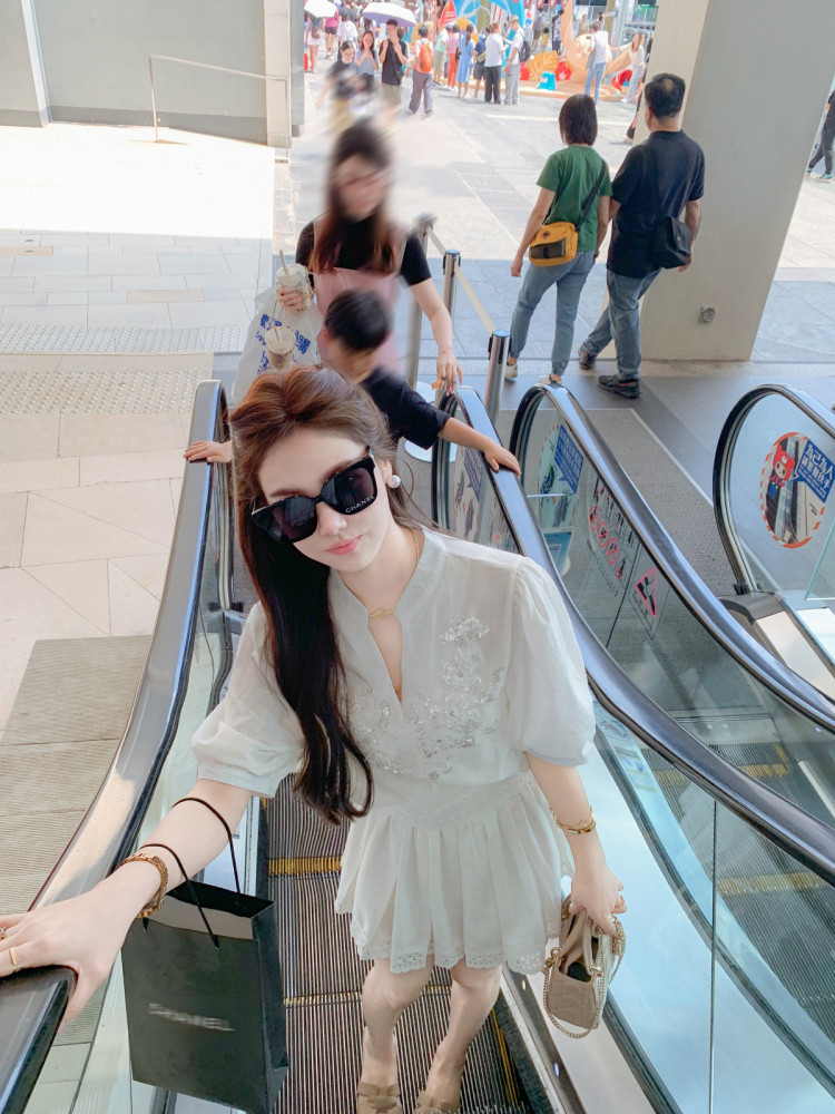 Woman wearing a white embroidered dress on an escalator