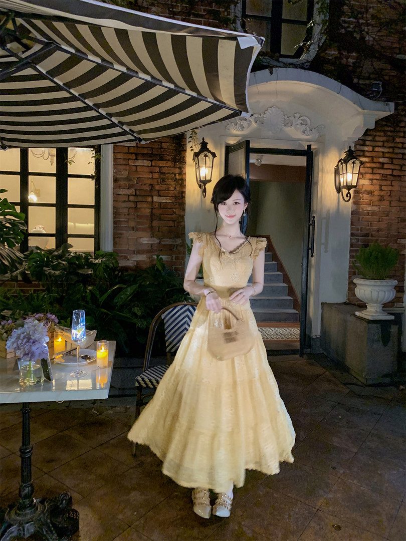 Woman wearing a pale yellow formal dress outdoors at night