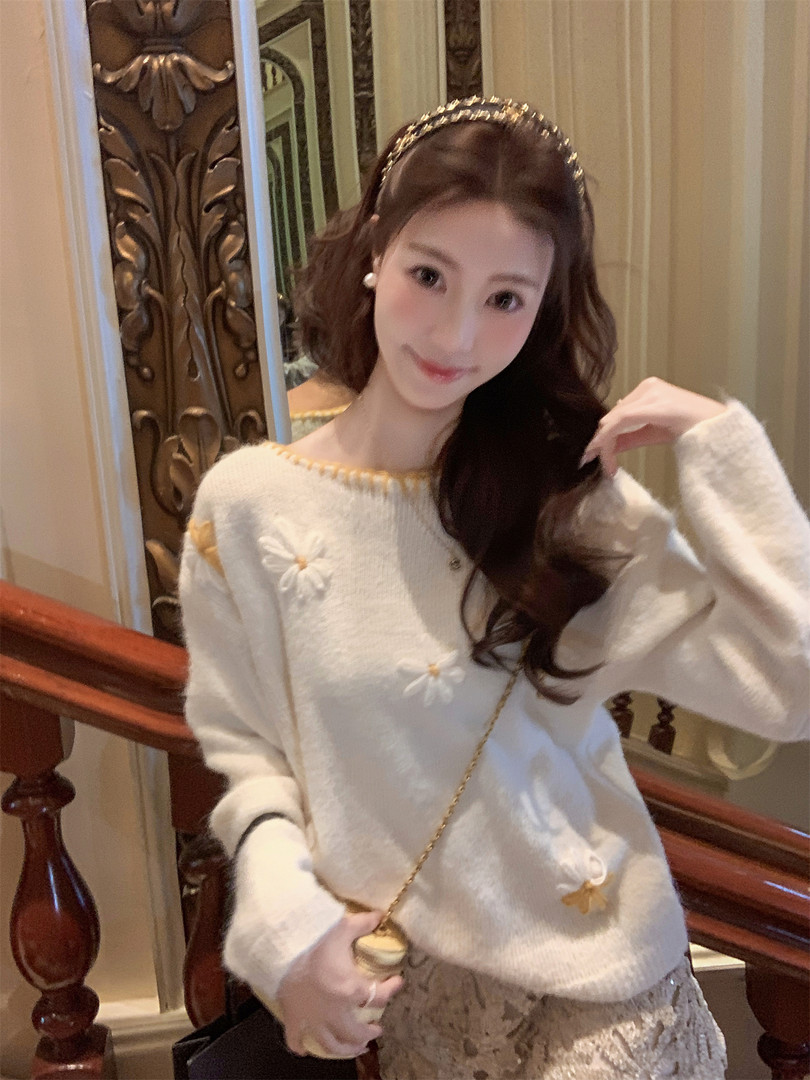 Woman modeling a cream fuzzy embroidered sweater with a gold chain bag
