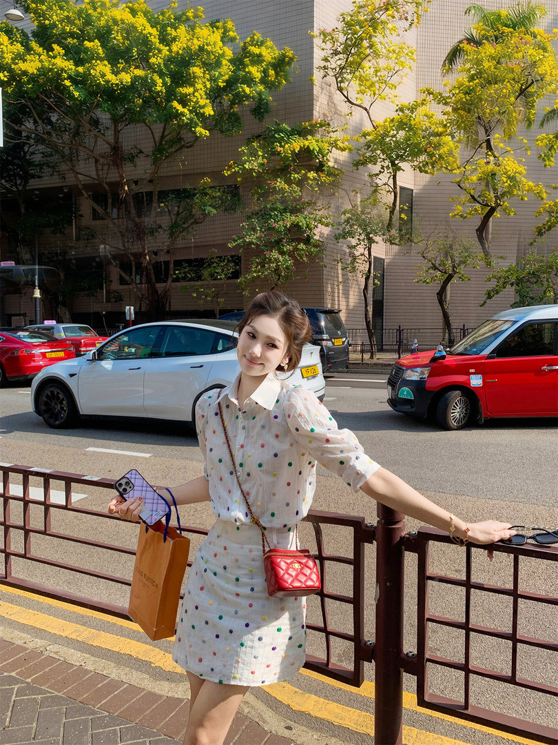 Woman wearing a white polka dot dress on a city street