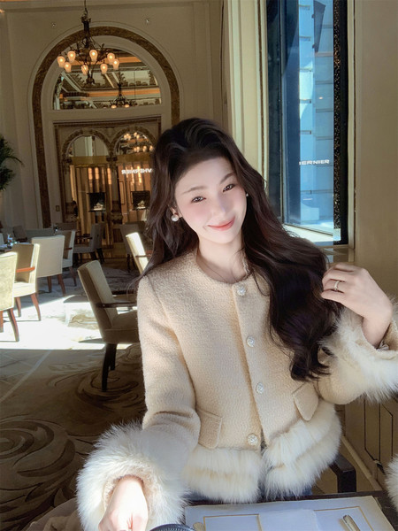Woman wearing a beige tweed coat with fur trim in a restaurant