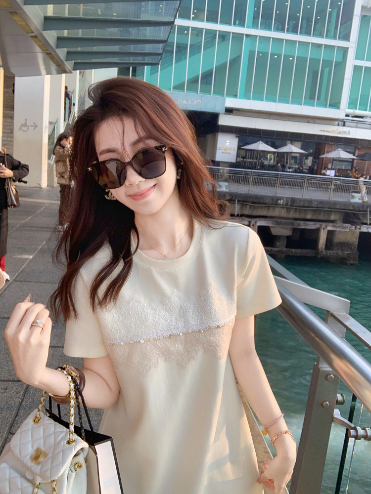 Woman wearing a light beige short-sleeve dress outdoors with sunglasses and a handbag