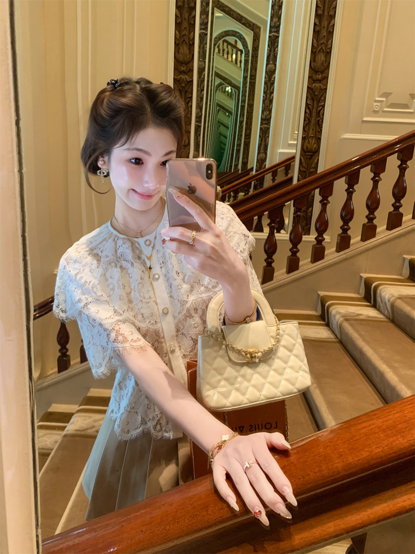 Woman wearing a white lace top and carrying a cream quilted handbag
