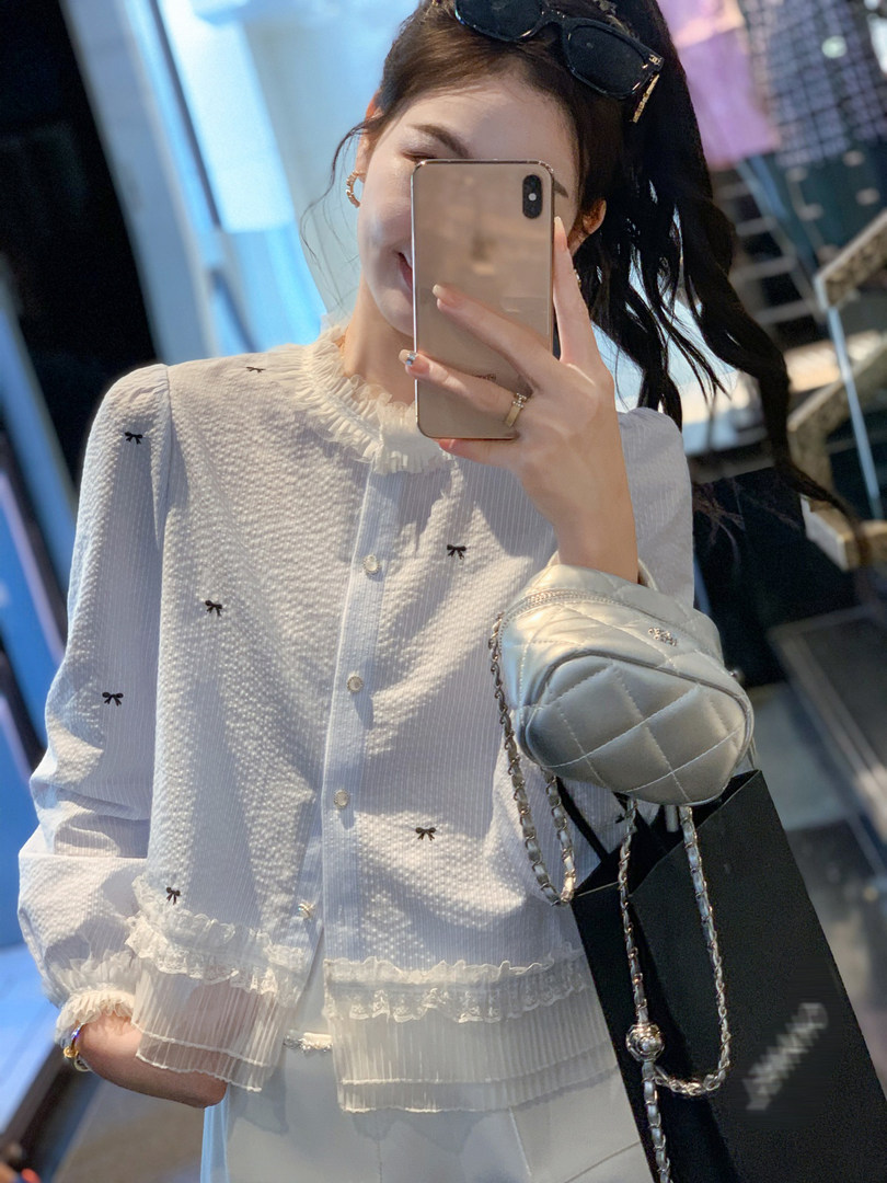 White ruffled blouse with small bow details worn by a model