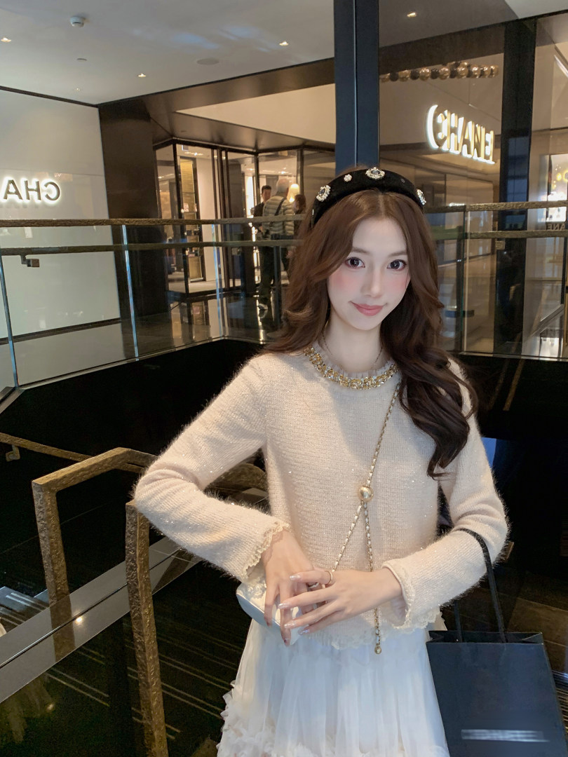 Woman wearing a cream knit top and white skirt with a black embellished headband