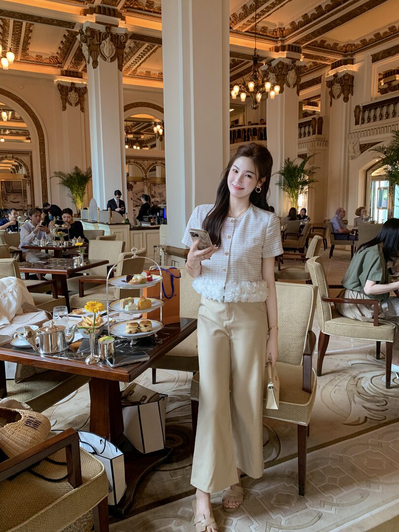 Woman wearing a light tweed top and beige wide-leg pants in a luxury hotel restaurant