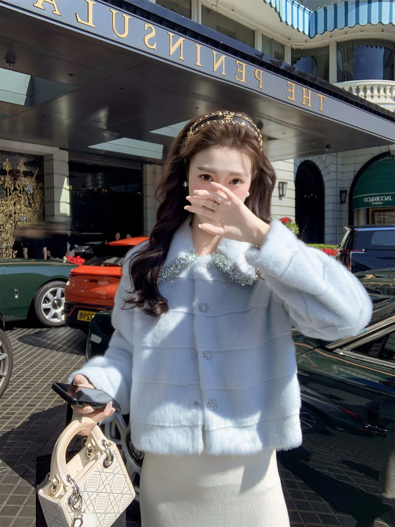 Woman wearing a light blue fluffy embellished jacket and skirt outside a hotel