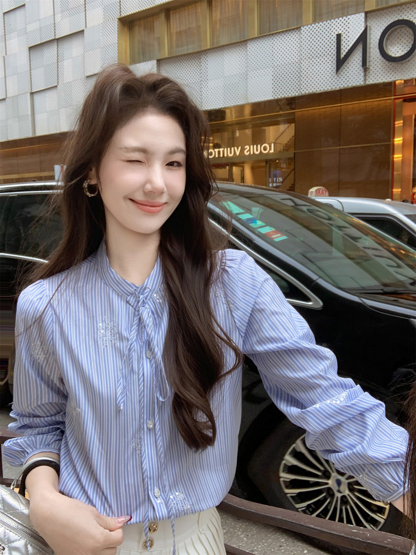 Model wearing a light blue striped button-up blouse
