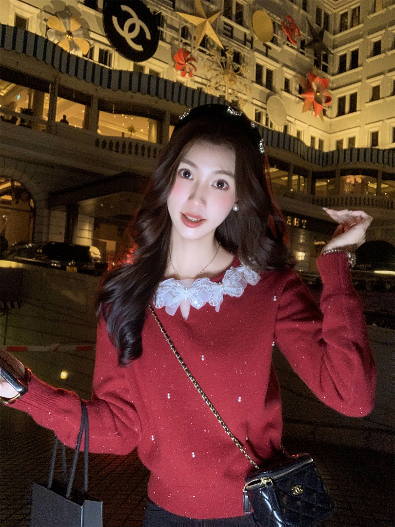 Woman wearing a red knit sweater with a white lace collar in a festive nighttime setting