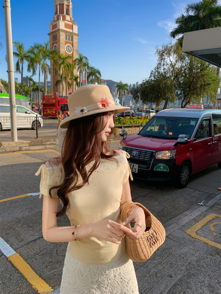 Woman wearing a beige summer outfit with a straw hat and woven handbag