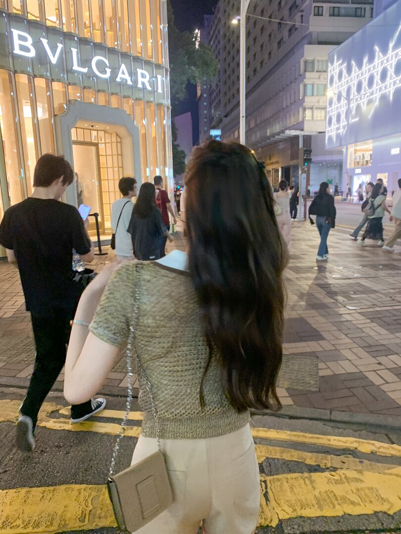 Woman wearing a textured short-sleeve top and light pants on a city street at night