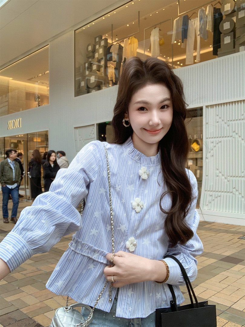 Woman wearing a light blue striped blouse with floral buttons