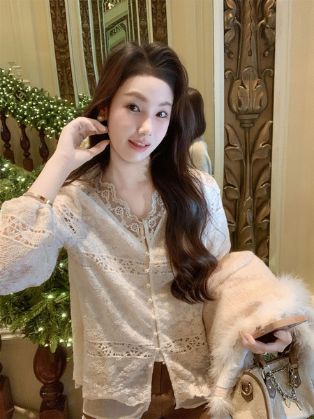 Woman wearing a white lace cardigan and holding a fur-trim handbag