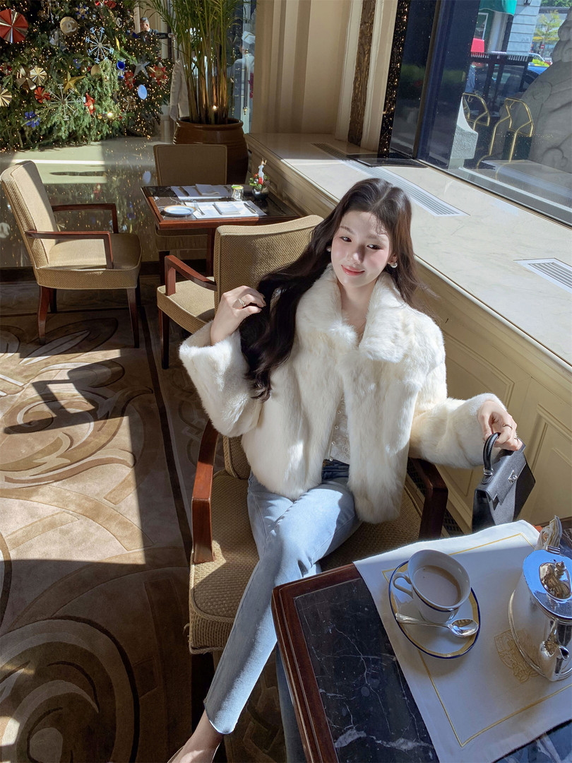 Woman wearing a white fluffy winter coat seated in a restaurant