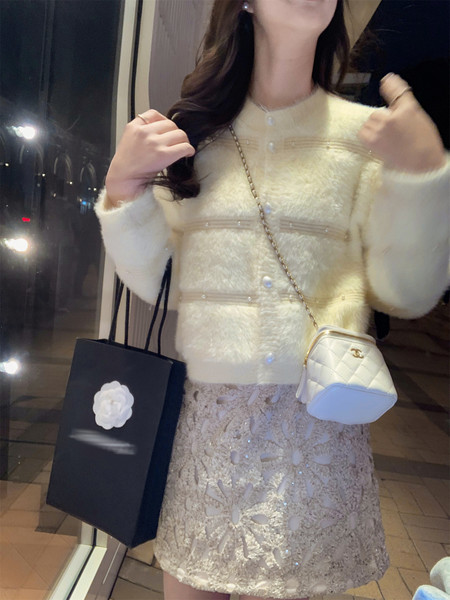 Woman wearing a cream fuzzy cardigan with a lace skirt and quilted mini bag