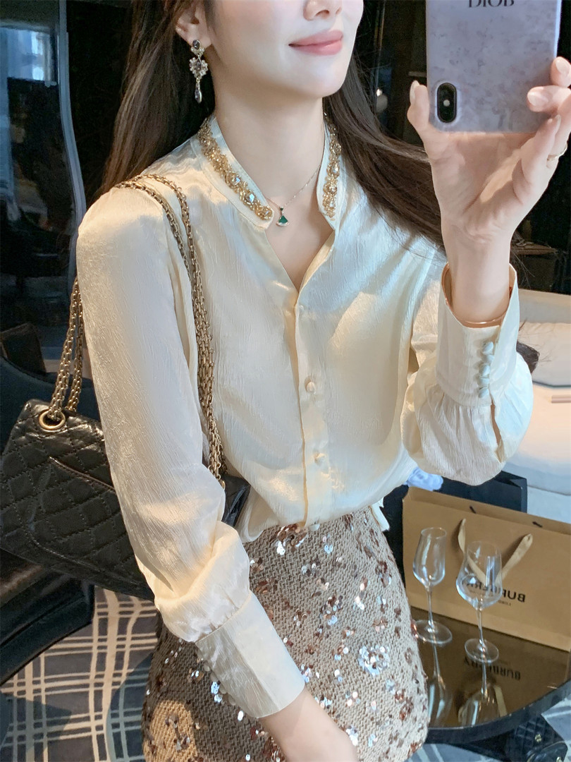 Woman wearing a cream satin blouse with a sequined skirt and black chain-strap handbag