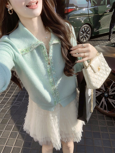 Woman wearing a pastel blue embellished cardigan with a white tulle skirt and quilted handbag