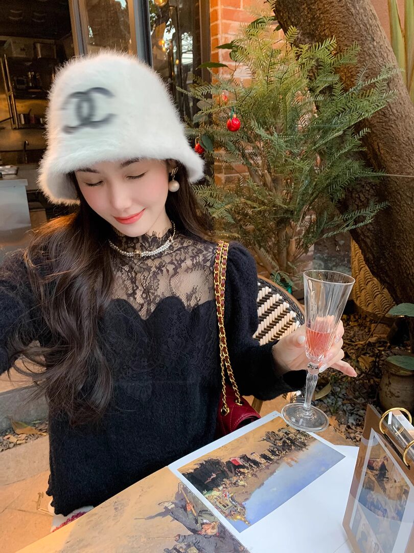 Woman wearing a black lace top and fuzzy white hat while holding a glass