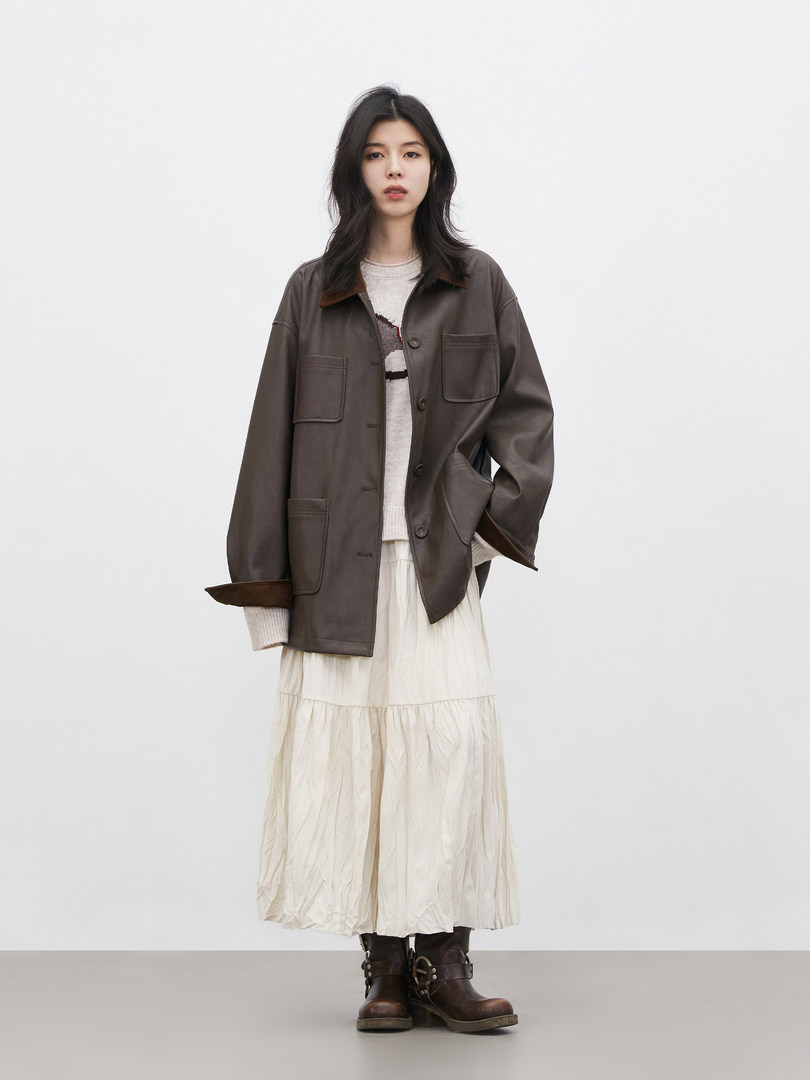 Model wearing a dark brown jacket with a cream skirt and boots