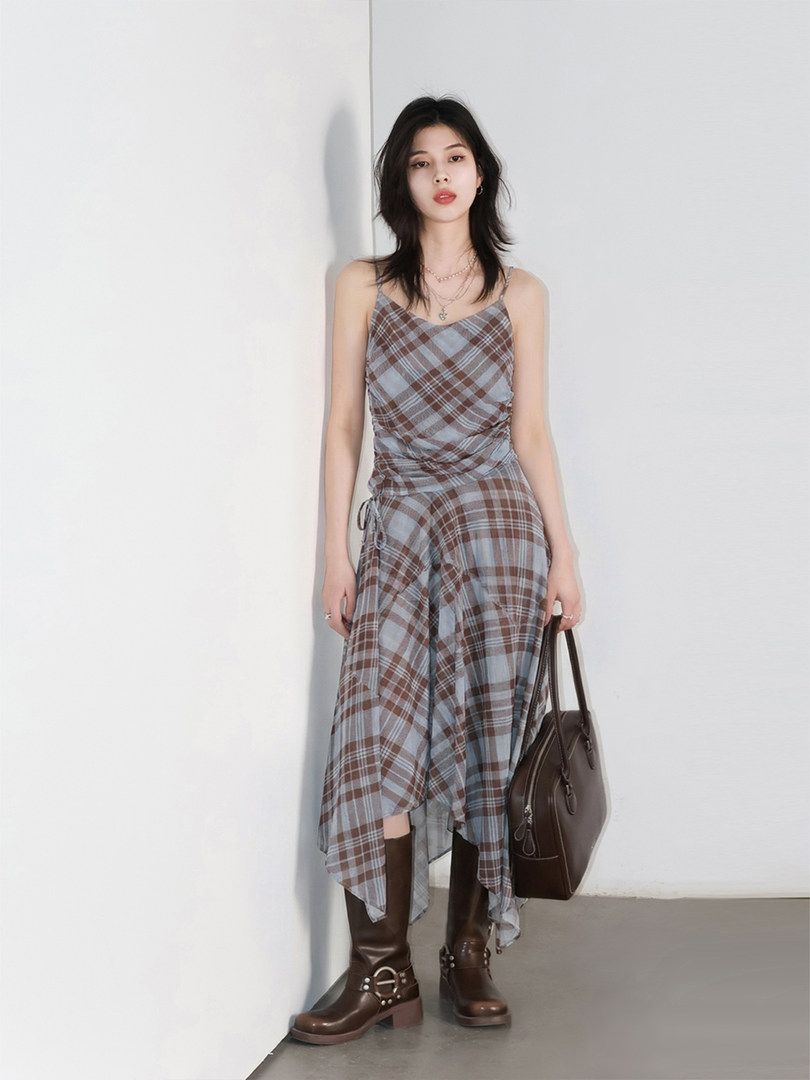 Plaid asymmetrical dress worn by a model with boots and a handbag