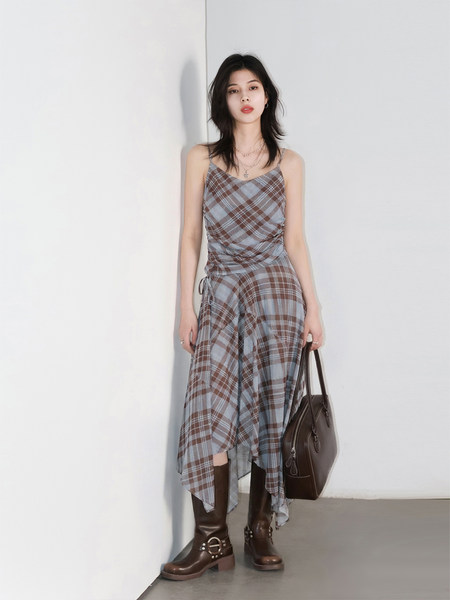 Plaid asymmetrical dress worn by a model with boots and a handbag