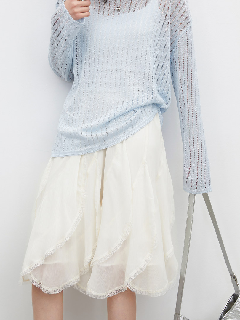 Model wearing a light blue sheer long-sleeve top with a cream layered skirt