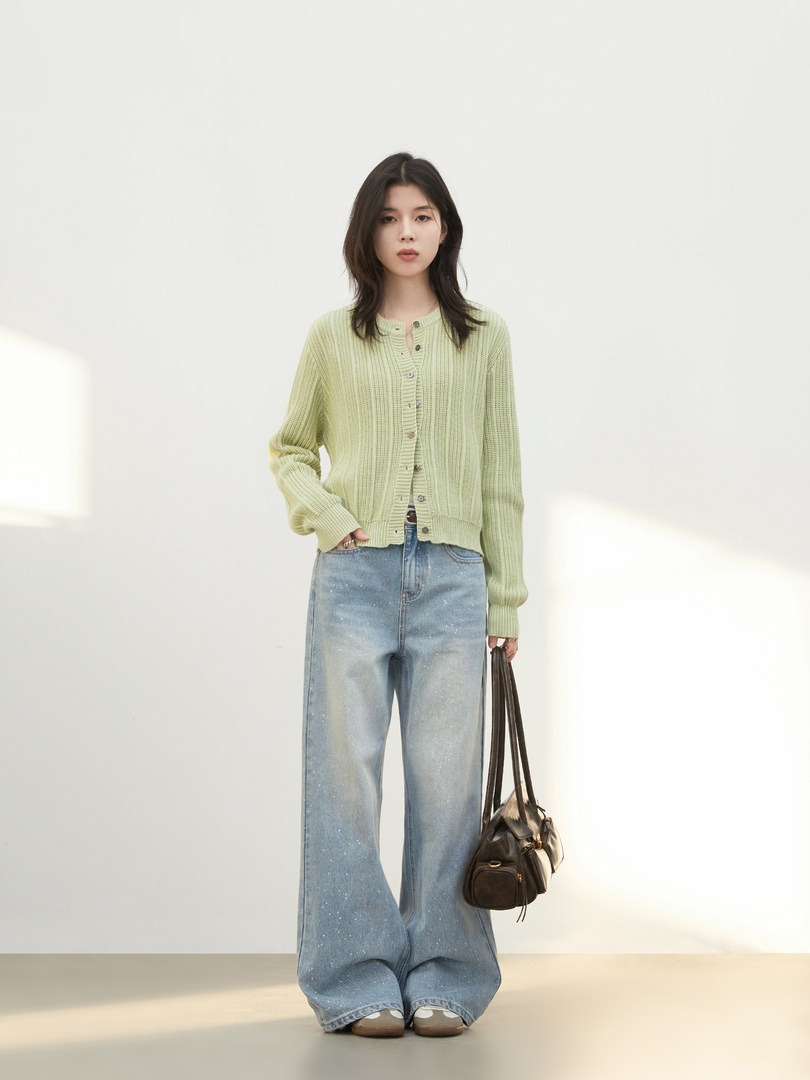 Model wearing a light green knit cardigan with wide-leg blue jeans and a brown shoulder bag
