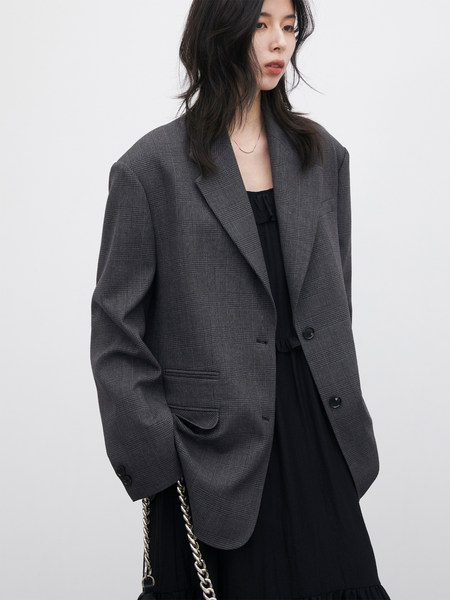 Model wearing a gray plaid blazer over a black dress
