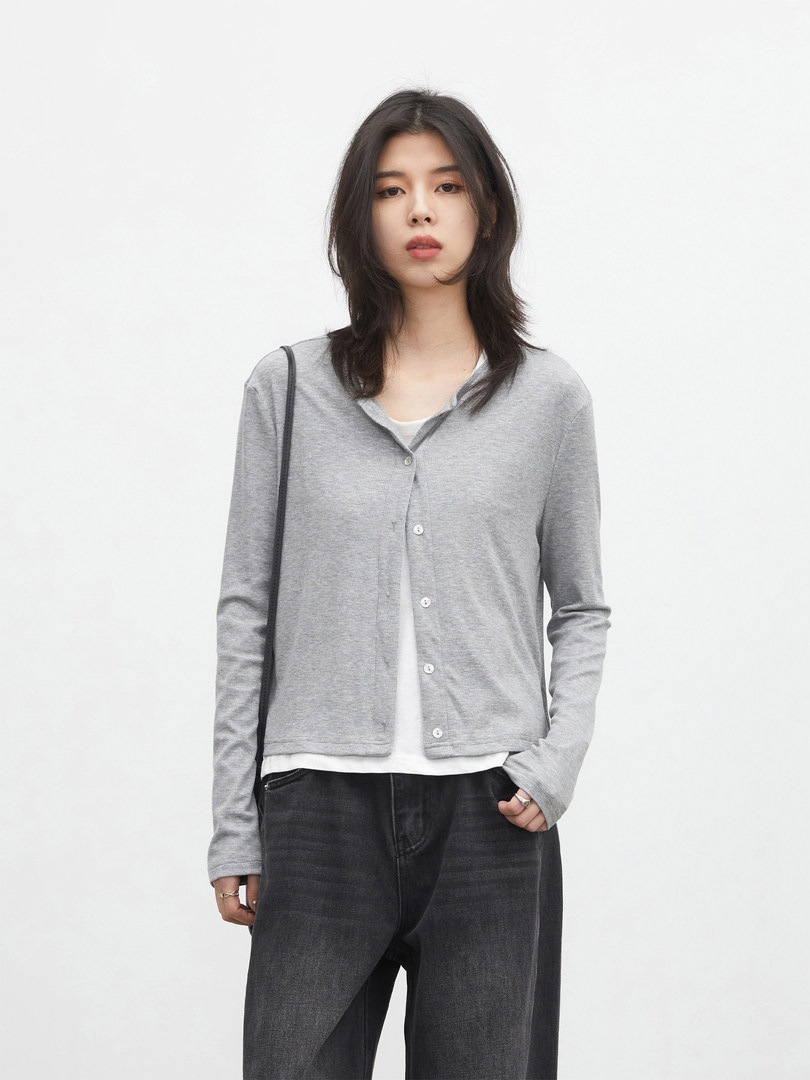 Model wearing a gray button-front cardigan over a white top with black jeans