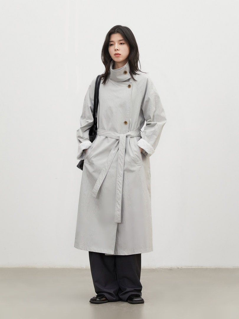 Model wearing a light gray belted trench coat