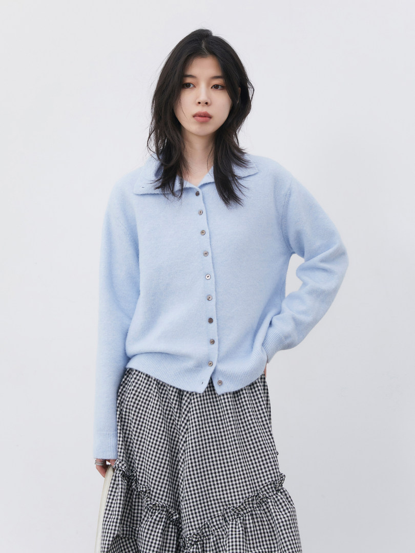 Model wearing a light blue button-front cardigan with a black-and-white gingham skirt