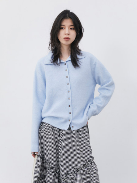 Model wearing a light blue button-front cardigan with a black-and-white gingham skirt