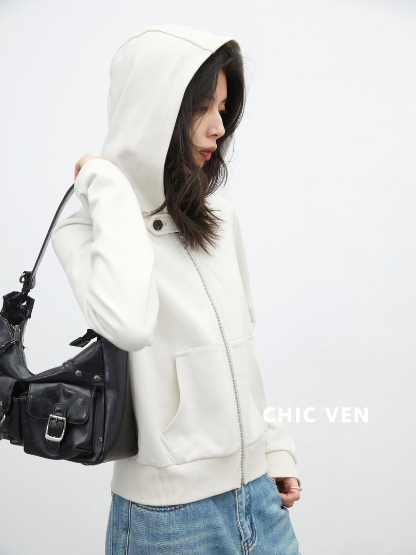 Woman wearing a white zip-up hooded sweatshirt with a black shoulder bag