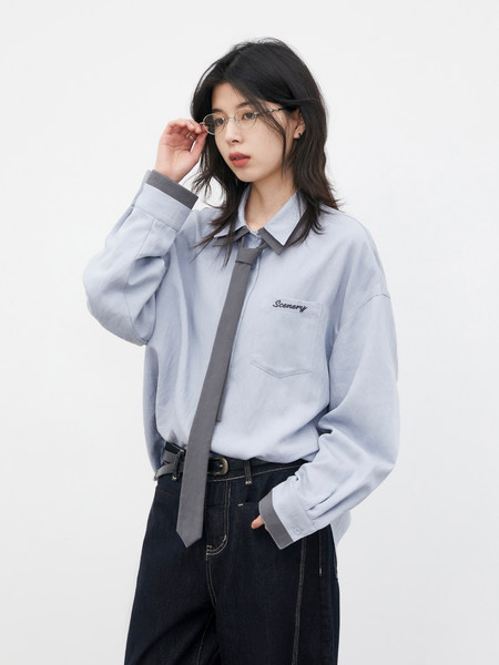 Model wearing a light blue oversized shirt with a gray tie and dark pants
