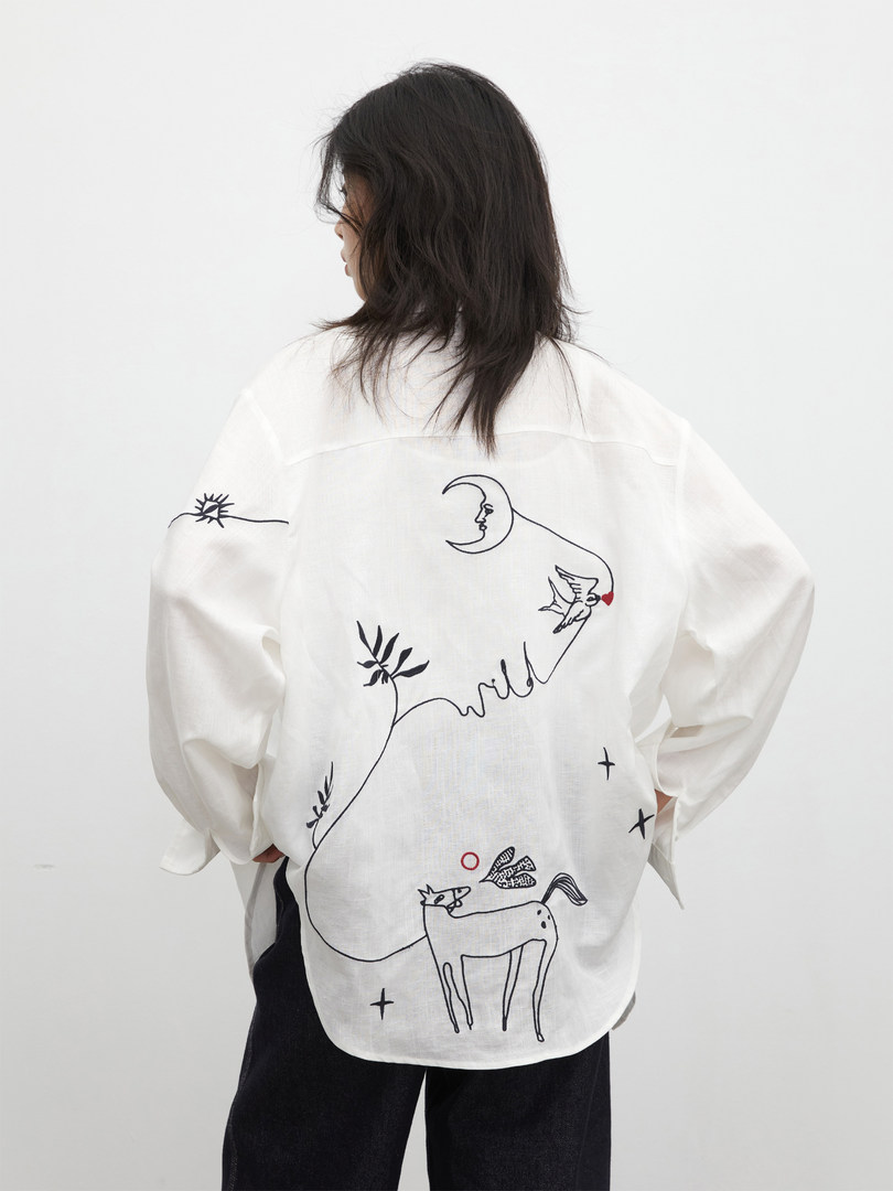 White oversized long-sleeve shirt with abstract black line-art print worn by a model