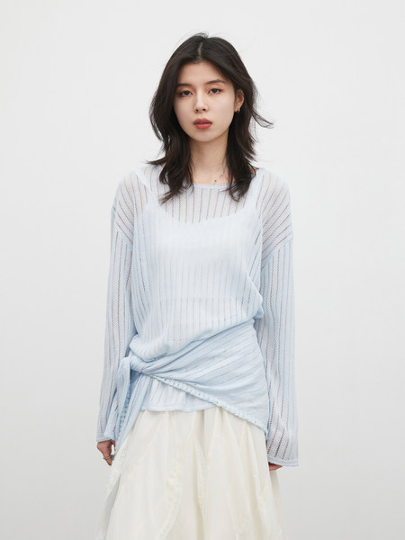 Model wearing a light blue sheer long-sleeve top with a cream skirt