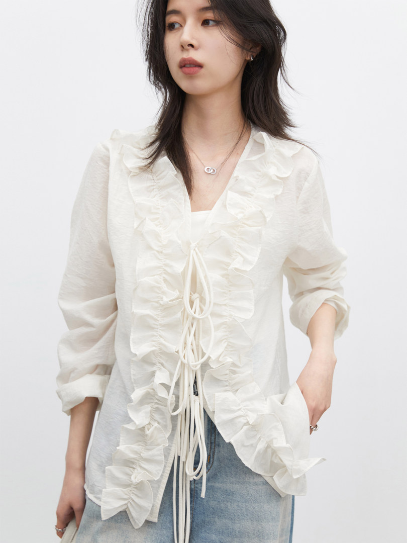 Woman wearing a white ruffled sheer blouse