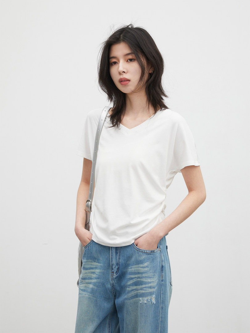 Model wearing a white V-neck T-shirt with blue jeans