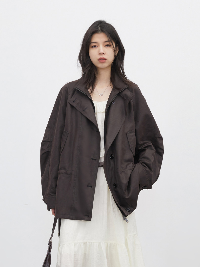 Model wearing a dark oversized jacket over a white dress