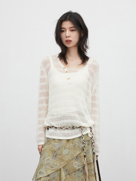 Model wearing a white sheer knit top with a patterned skirt