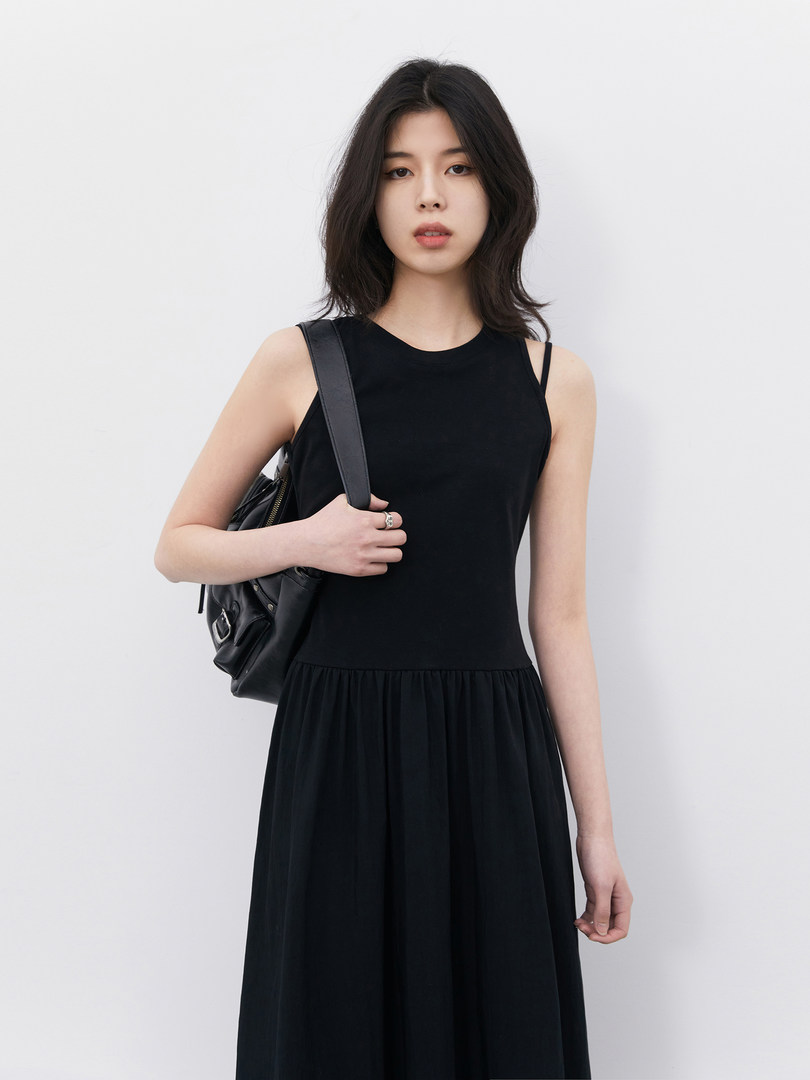 Model wearing a black sleeveless long dress with a black shoulder bag