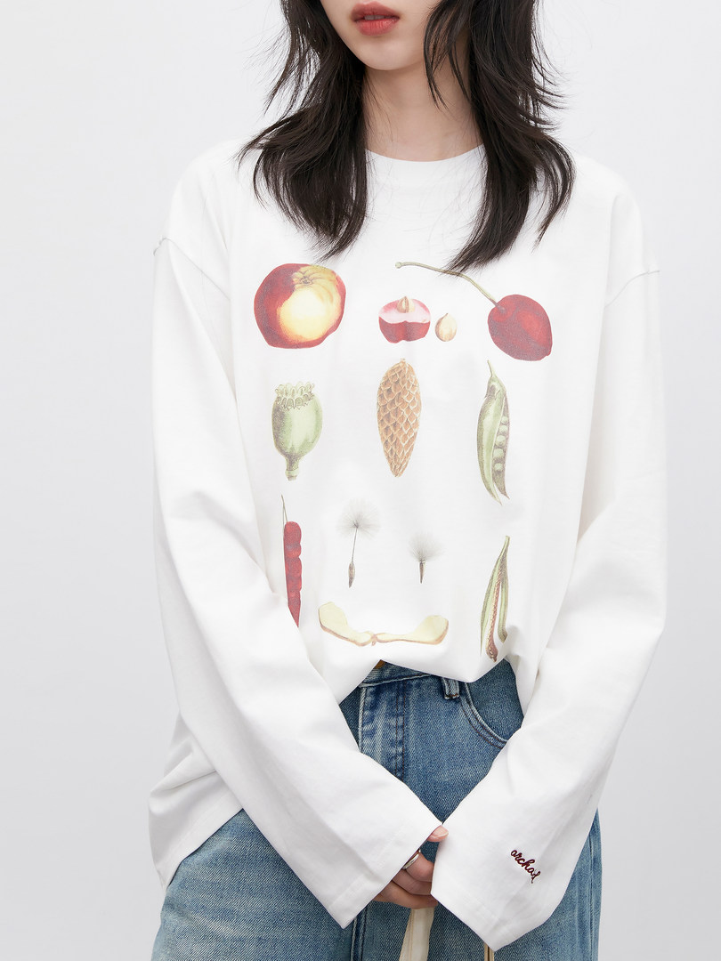 White long-sleeve graphic shirt with fruit and plant illustrations worn by a model
