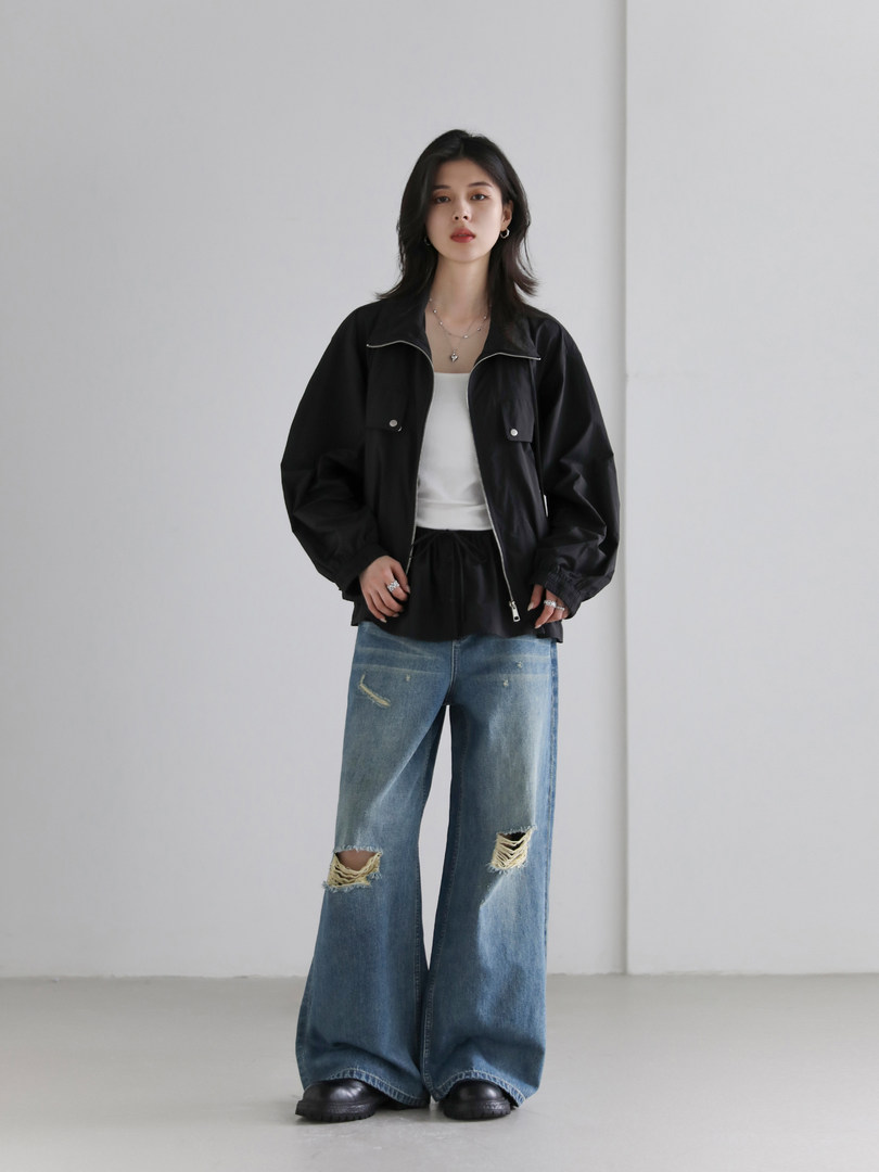 Model wearing a black jacket with a white top and distressed wide-leg jeans
