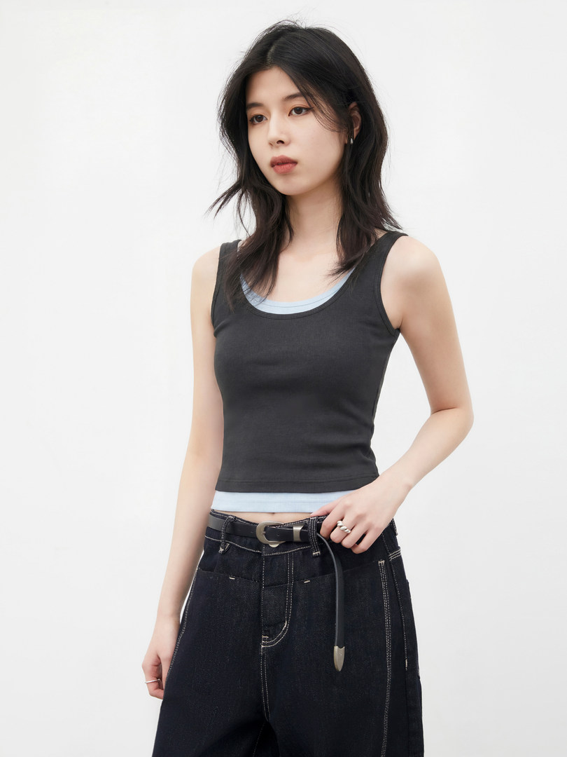 Model wearing a black sleeveless tank top with dark jeans