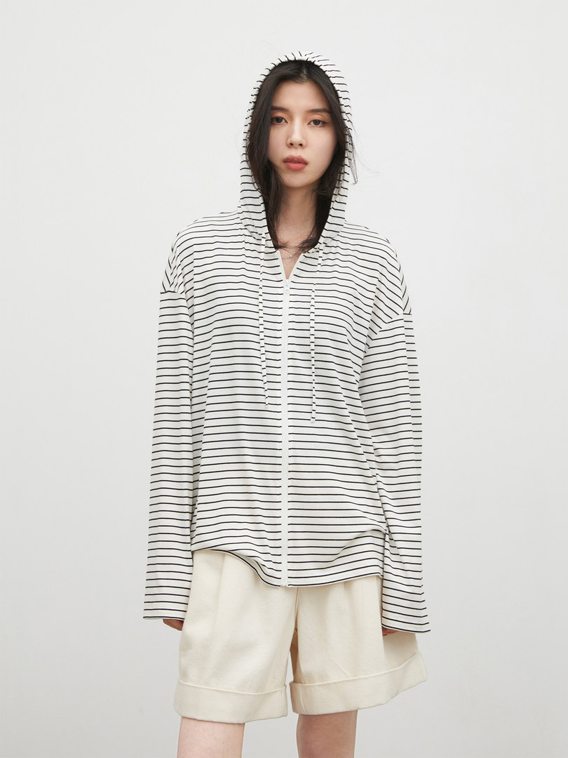 Model wearing a white-and-black striped hooded zip-up top with cream shorts