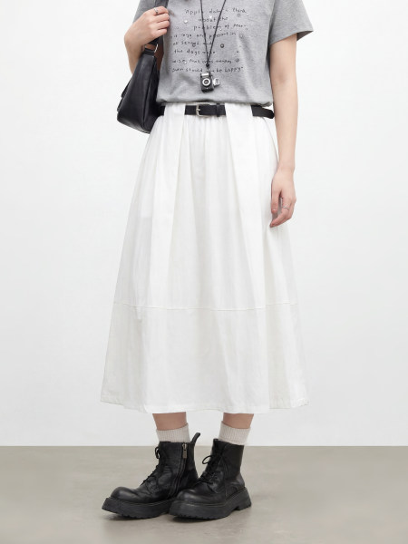 Model wearing a gray graphic T-shirt, white midi skirt, and black combat boots
